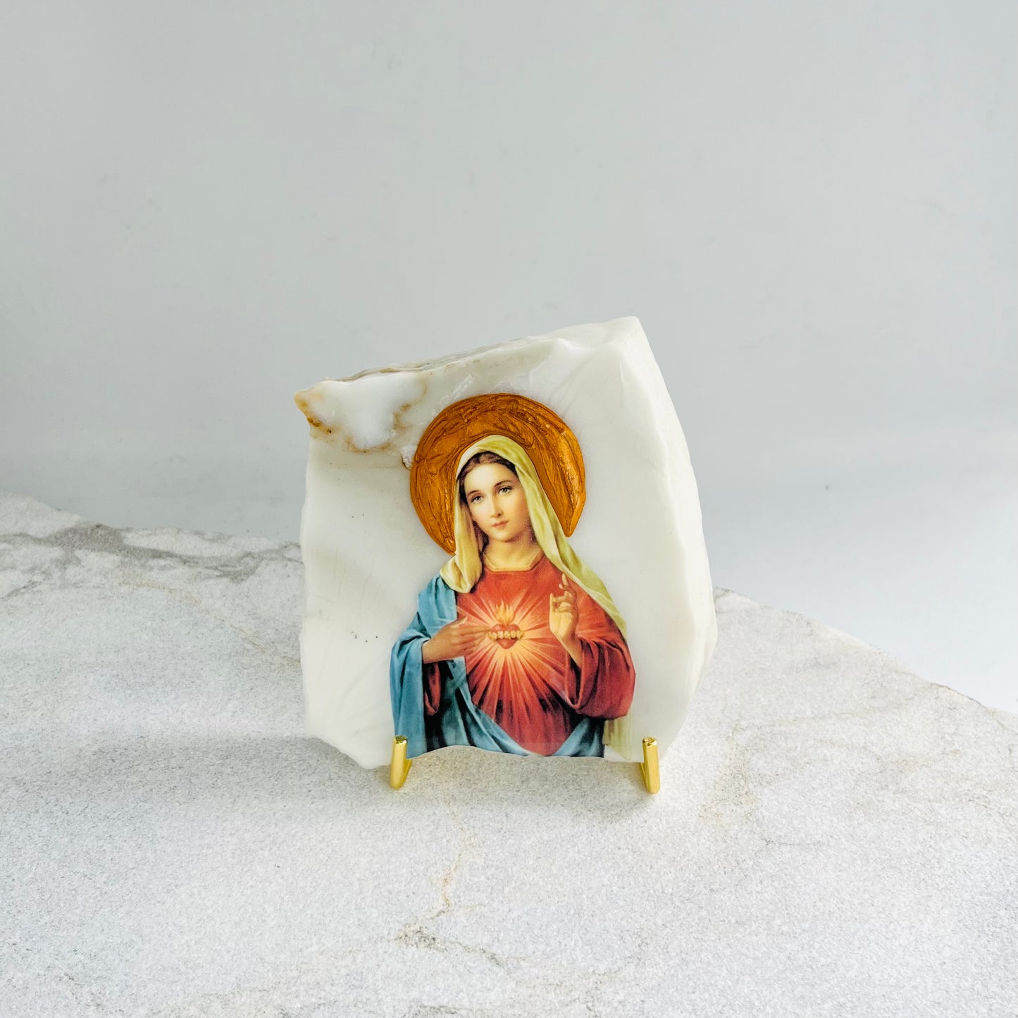 Mary Sacred Heart is carefully handcrafted on Calacutta Marble covered with a clear hypoxy resin.  Comes with a white stand.