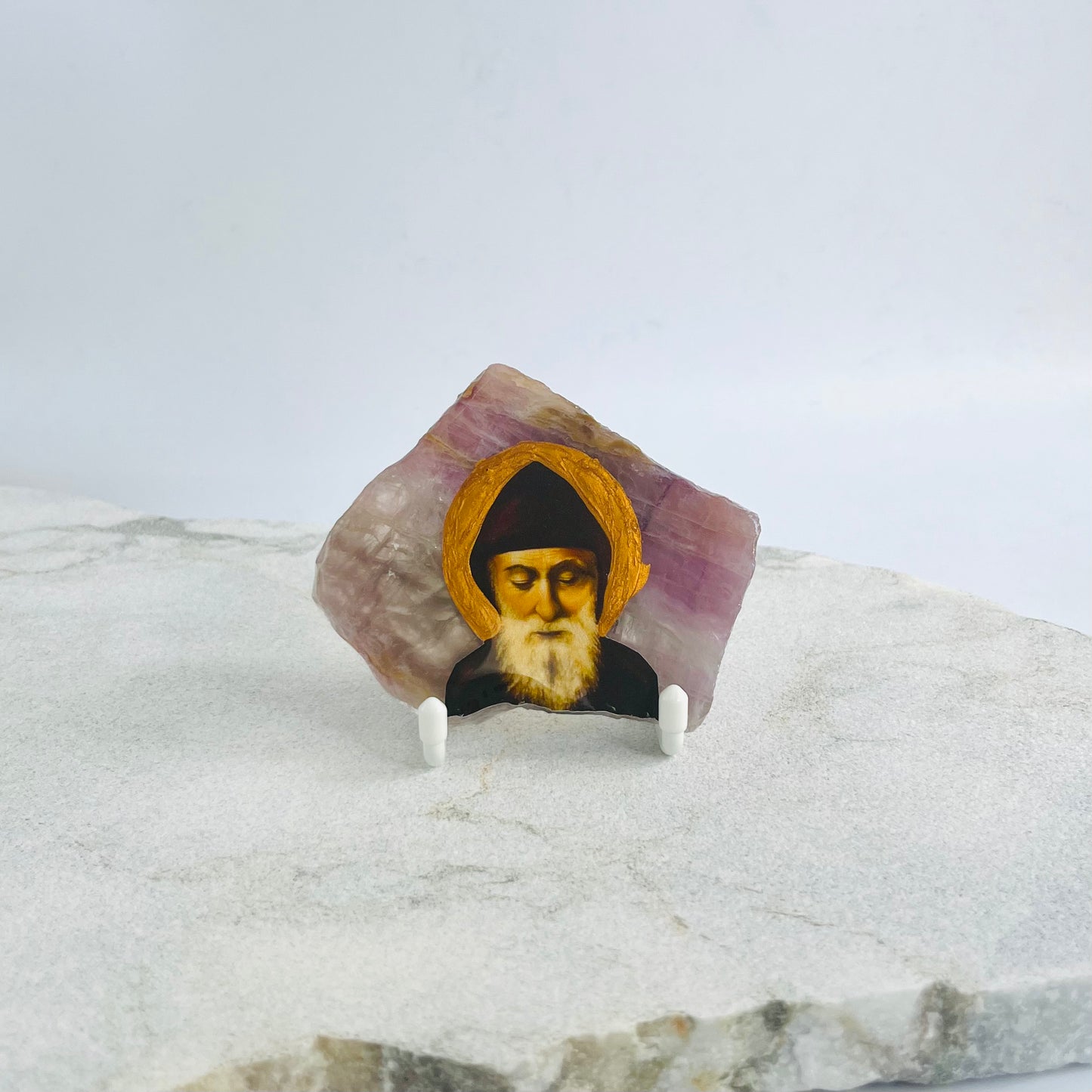 Saint Charbel Maronite Icon is carefully handcrafted on Seven Slabs Crystal, covered with a clear hypoxy resin.  Comes with a white stand.